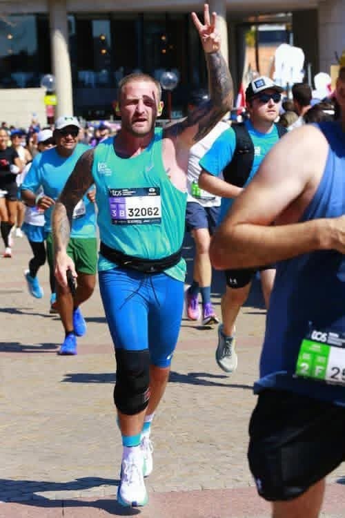 Denny running in Sydney with three fingers raised for his third star
